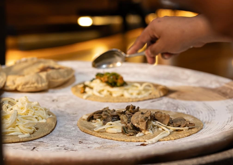 Preparación de tortillas con queso y hongos sobre el comal de Chapulín.